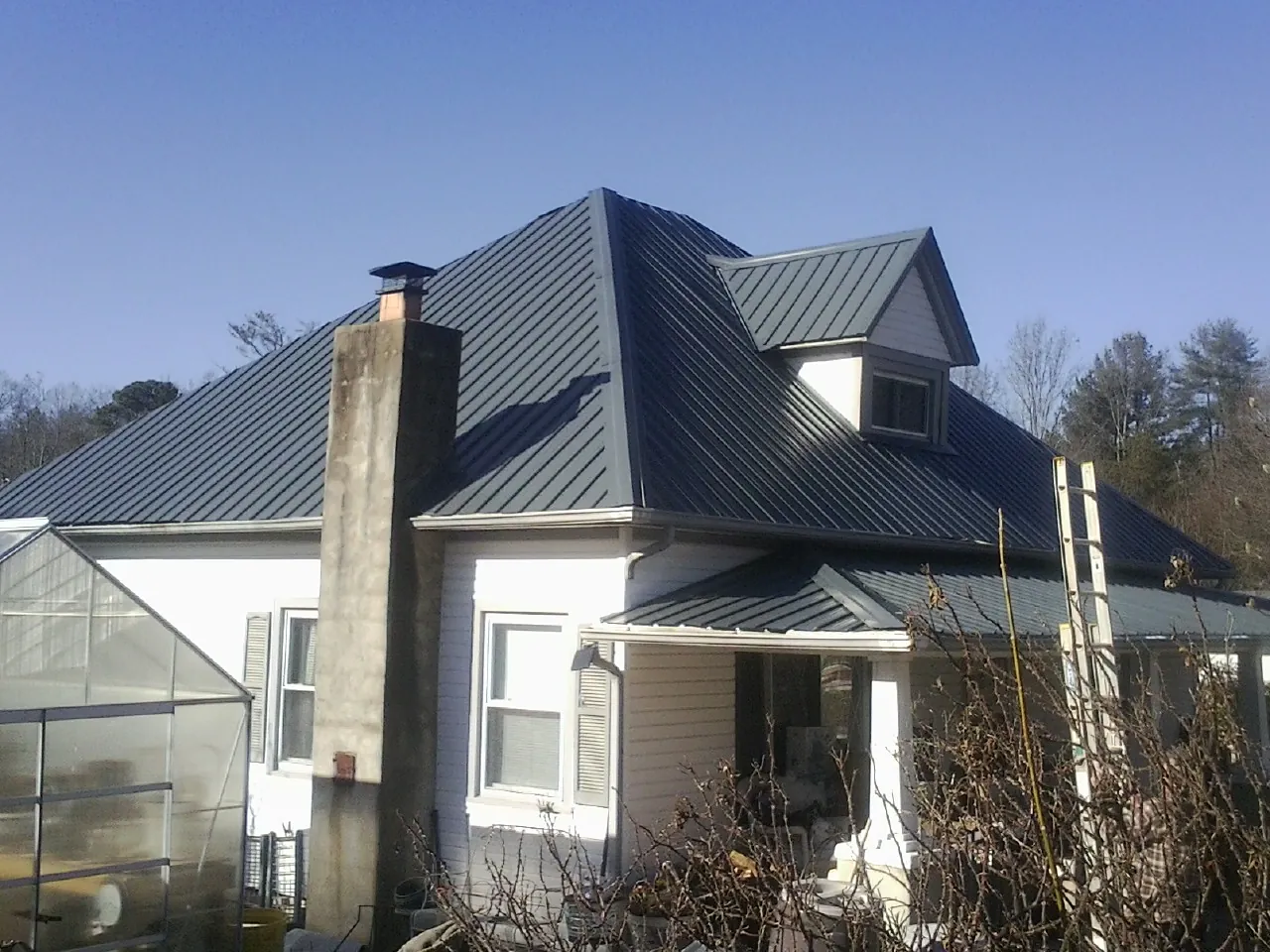 Dark blue standing seam metal roof on a white farmhouse with dormer — Slate & Tile Roof Repair by Roofing Brothers in Lobelville