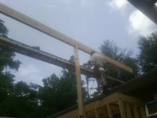 Carpenter setting a ridge beam over a new addition frame — Ice Dam Removal by Roofing Brothers in Lobelville