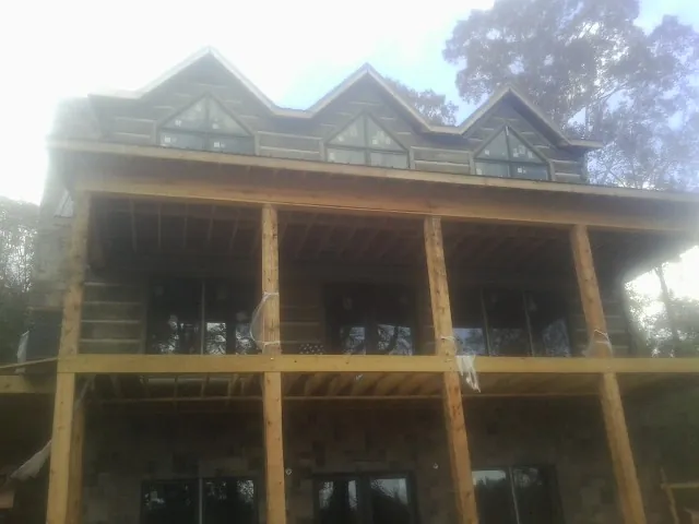 Dormers and porch framing on a large log home under construction — Roof Coating work by our crew in Lobelville