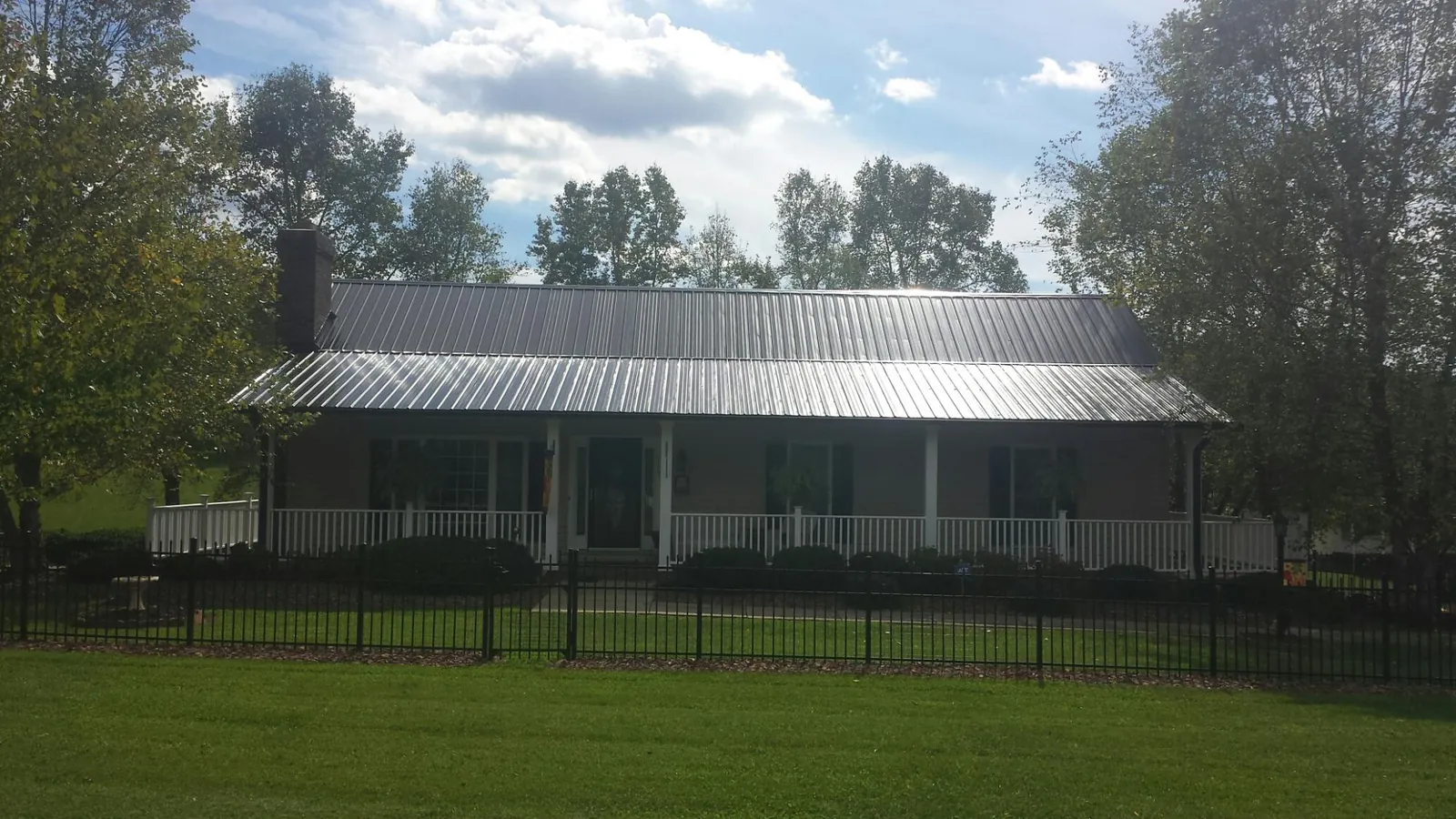 Gray metal roof on a brick ranch with a full width front porch — Gutter Guard Installation work by our crew in Lobelville
